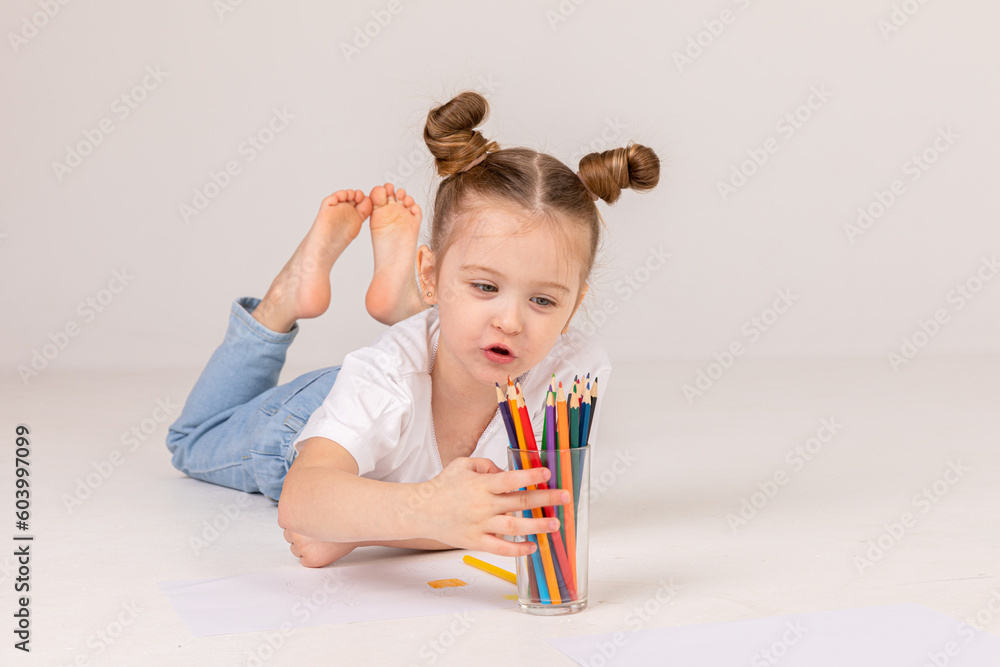 A little girl draws with colored pencils on the floor. High quality A little girl draws with colored pencils on the floor. High quality