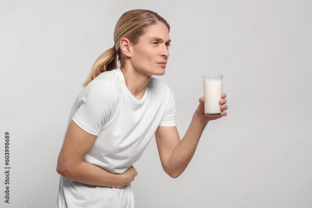 Woman with glass of milk suffering from lactose intolerance on white background Woman with glass of milk suffering from lactose intolerance on white background