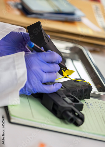 Police scientist writes serial number on firearm magazine in crime lab, conceptual image