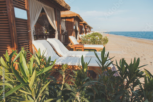 Fototapeta Naklejka Na Ścianę i Meble -  sun loungers and beach pavilions on the shores of the mediterranean sea, the concept of relaxation, holidays in a hotel on a sandy beach.