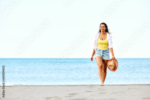 Young carefree woman enjoys in walk on sandy beach.