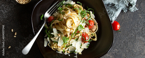 Foto plate of tagliatelle pasta with tuna and artichokes on a dark table