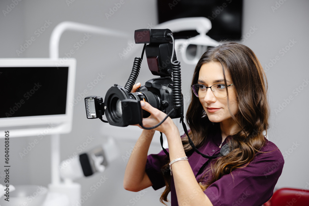 Portrait of female dentist holding photo camera in hands, standing in dental office