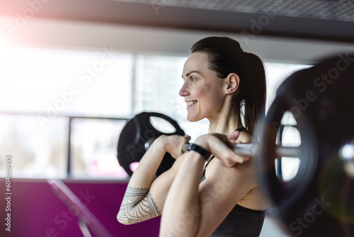 Young woman working out with a barbell at the gym 

