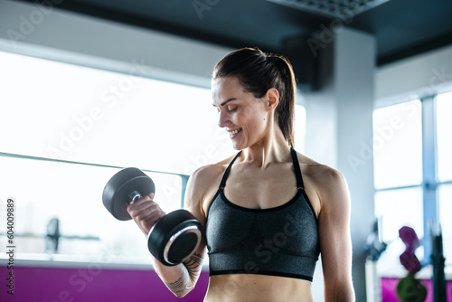 Young woman exercising with dumbbells in a health club 