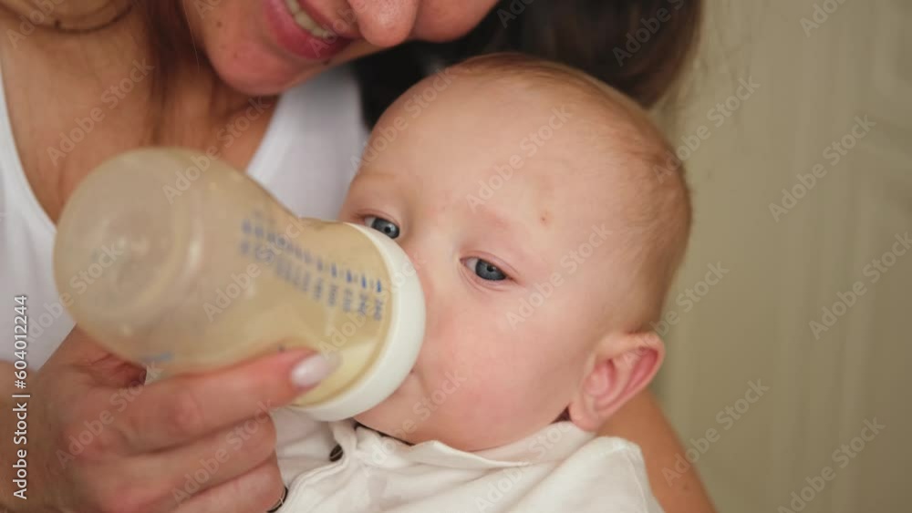 Happy family at home. Mother holding little baby toddler child feeding milk from bottle. Newborn Infant baby girl sucking eating drinking milk. Mom of breast feeding baby. Motherhood happy child Happy family at home. Mother holding little baby toddler child feeding milk from bottle. Newborn Infant baby girl sucking eating drinking milk. Mom of breast feeding baby. Motherhood happy child