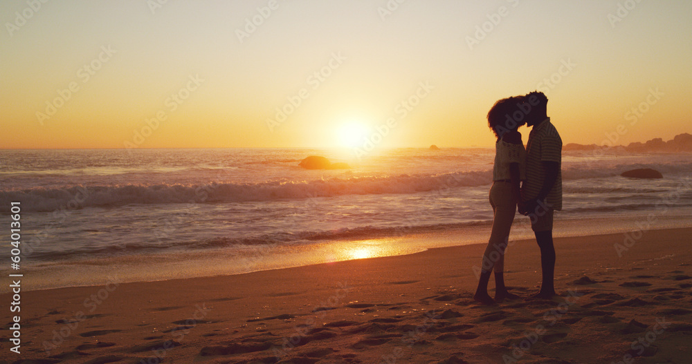 Sunset, kiss and silhouette of couple at the beach for bonding, date or holiday in Bali. Care, dark and a man and woman kissing at the ocean together for love, romance or vacation freedom by the sea