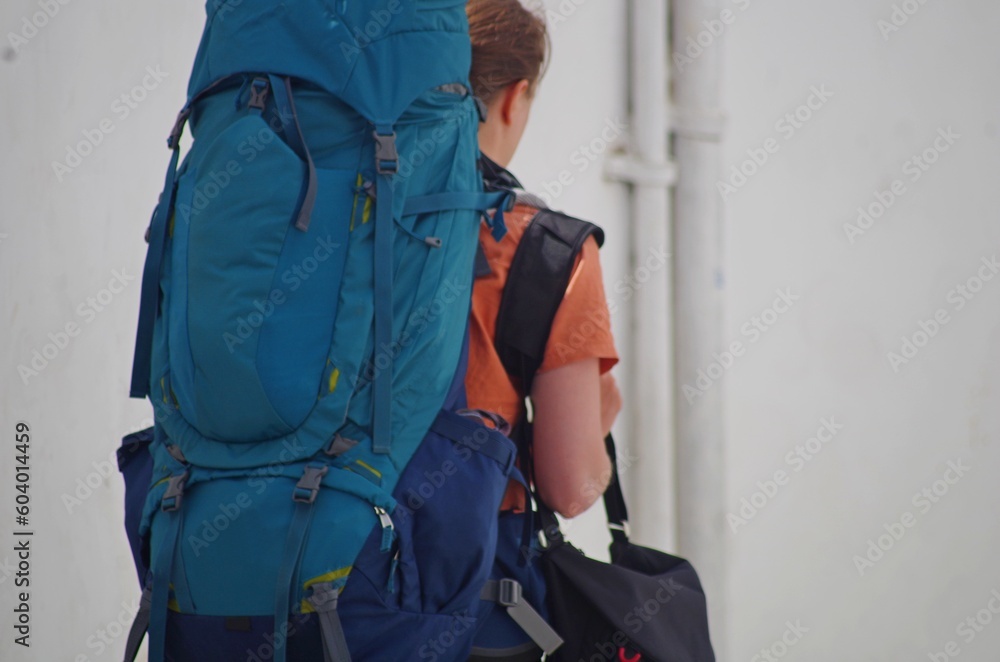 Woman with a huge blue tourist backpack on her back Woman with a huge blue tourist backpack on her back