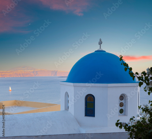 Classical Greek church architecture. Sunset view of the white church with blue domes. Important travel destinations in Greece. Santorini island.