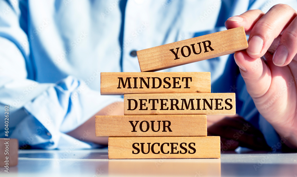 Close up on businessman holding a wooden block with "Your mindset determines your success" message - obrazy, fototapety, plakaty 