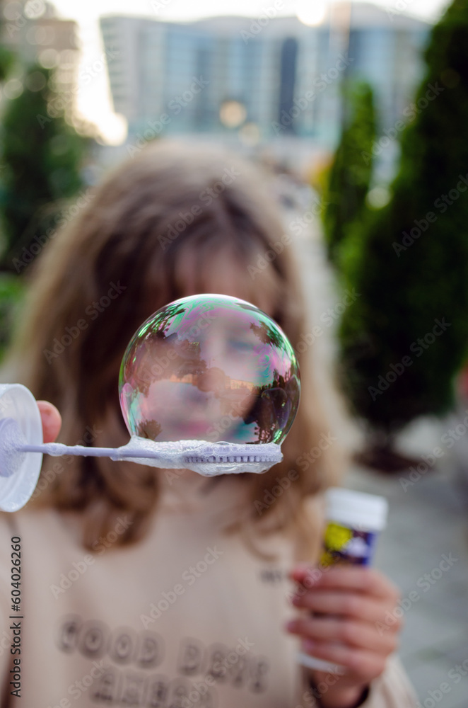 The child blows bubbles, focus on the bubble, the face in the bubble, close-up, stock photo
