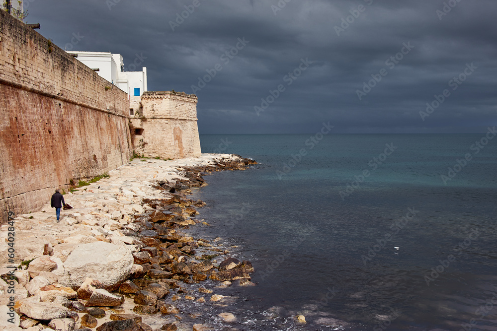 Lonely man walking on a rainy day on the seafront of Monopoli in Puglia
