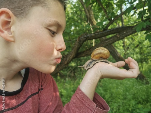 a snail crawls on a child's hand. Young boy have a snail friend photo