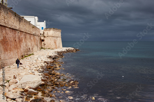 Lonely man walking on a rainy day on the seafront of Monopoli in Puglia