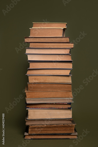 Tall tower made of old books on an olive green background.