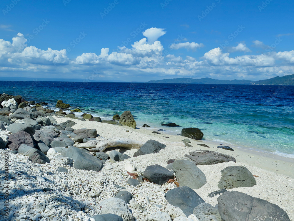 Stones on the beach. Blue sea coast, sandy beach, white clouds on the horizon.