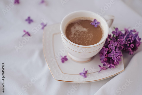 Cup of coffee with lilac flowers on a white background.