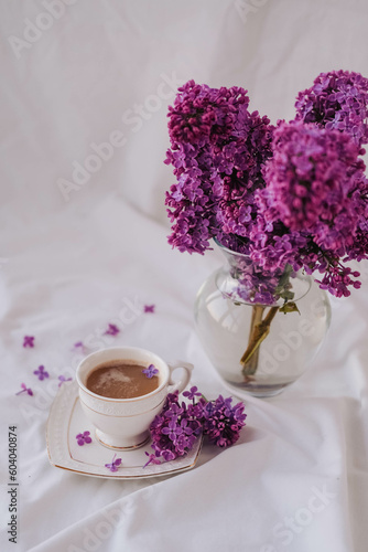 Cup of coffee with lilac flowers on a white background.