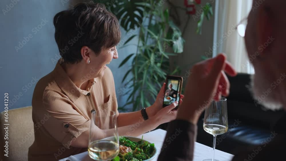 Smiling elderly woman shows photo on phone to her husband on date in cafe Smiling elderly woman shows photo on phone to her husband on date in cafe