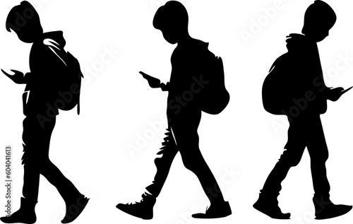 silhouette of schoolboy walking while looking down at his cell phone