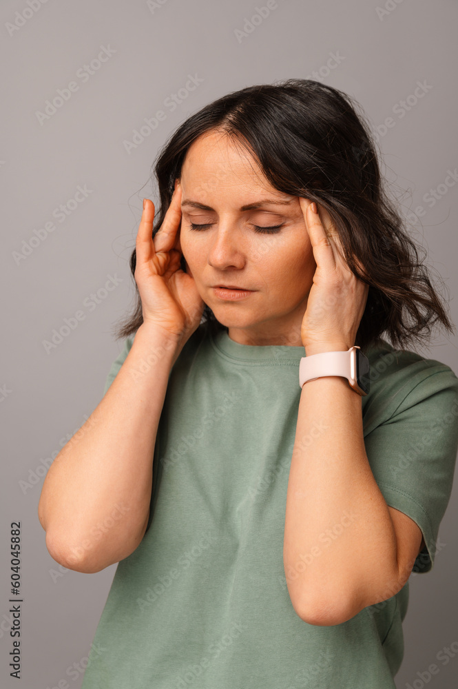 Vertical shot of a mid age woman having a head ache and holding hands on it. Vertical shot of a mid age woman having a head ache and holding hands on it.