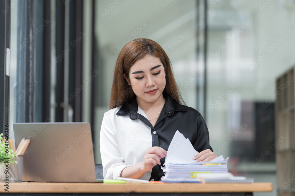 The busy work desk of a businesswoman is cluttered with stacks of paper files, folders, and papers as she searches and checks for unfinished documents, her hands moving swiftly over the paperwork. The busy work desk of a businesswoman is cluttered with stacks of paper files, folders, and papers as she searches and checks for unfinished documents, her hands moving swiftly over the paperwork.
