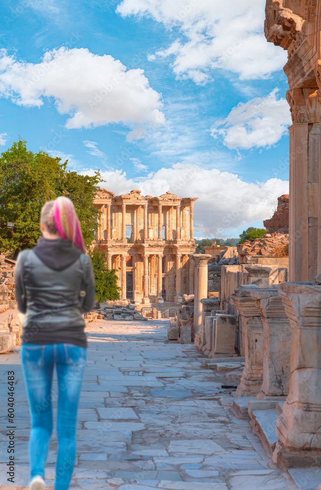 Beautiful woman in jeans watches the ruins of Ephesus -  Celsus Library in Ephesus - Selcuk, Turkey