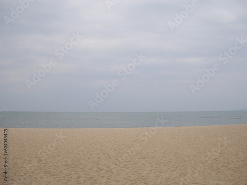 The peaceful atmosphere of the evening sea where the sky is not bright, the beach is full of human footprints. The uninhabited sea had small waves lapping on the sand. 