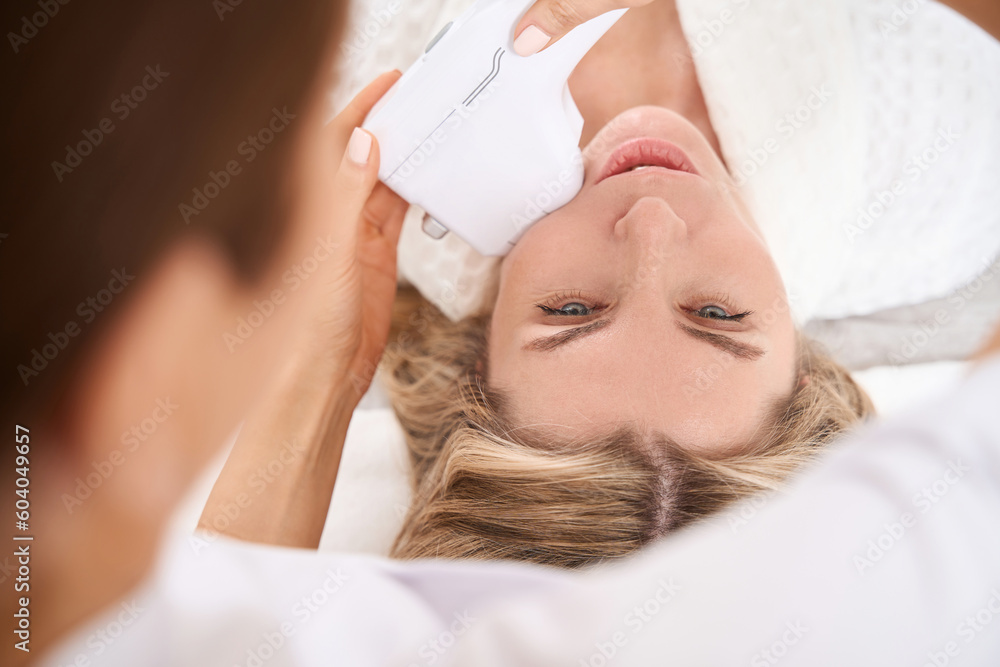 Female takes care of facial skin in clinic aesthetic medicine