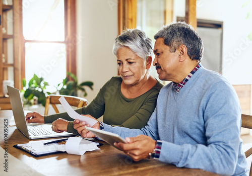 Senior couple, budget planning and health insurance checklist with computer at home. Documents, pension and elderly people with financial, tax and debt form in a house with bills and pc admin