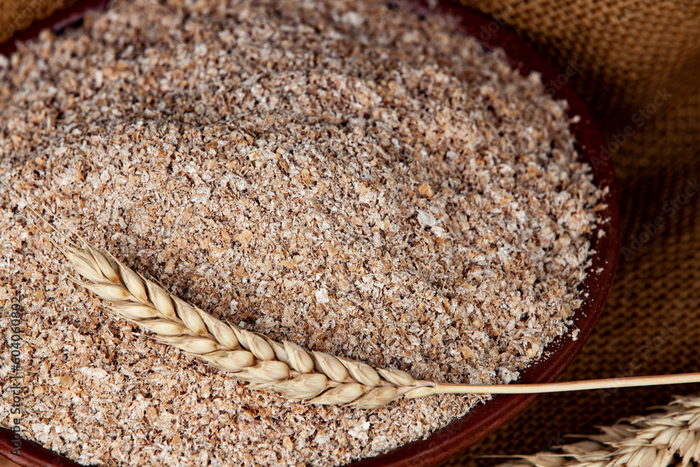 Wheat ear on a bowl of bran. Foodstuffs concept.
