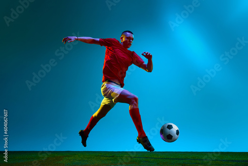 Portrait with one professional football  soccer player in sportswear playing  training over field  stadium background in neon light. Concept of team game  sport