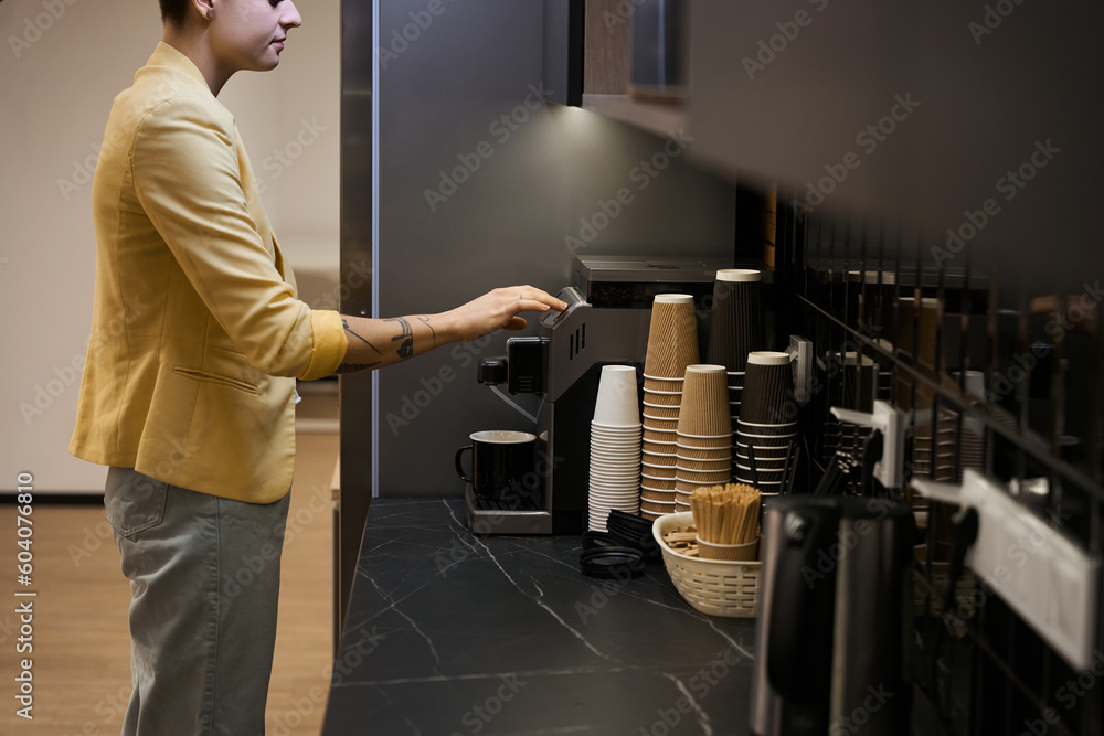 Woman making coffee in office coffee machine