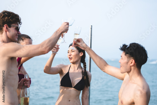 Man and woman friends group enjoy celebration party and fun luxury summer outdoor lifestyle by drinking champagne together, travel vacation on catamaran yacht boat sailing in tropical sea sunset on