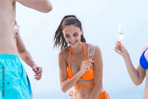 Man and woman friends group enjoy celebration party and fun luxury summer outdoor lifestyle by drinking champagne together, travel vacation on catamaran yacht boat sailing in tropical sea sunset on