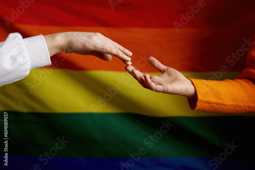 Hand reaching other hand over rainbow pride flag. Lgbtq intersex rights concept