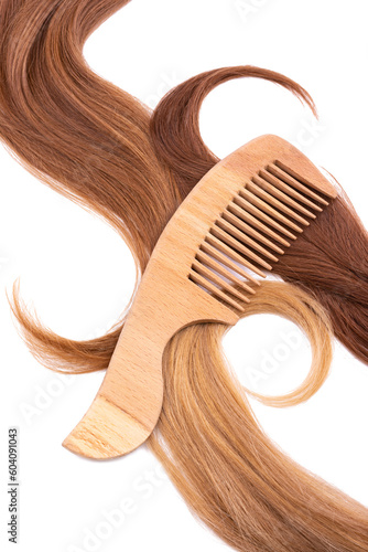 Wooden comb on natural curls of dark and light blond hair. Isolated on white background. The concept of comprehensive hair care, the provision of hairdressing services, maintaining hair health