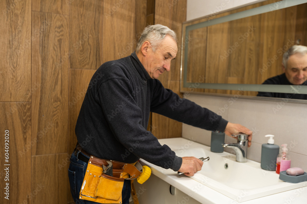 Plumber is repairing a faucet with water in the bathroom Plumber is repairing a faucet with water in the bathroom