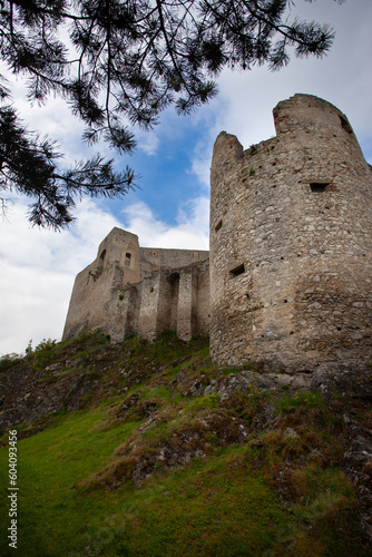 Low angle view of the circular tower of a castle in ruins. Architectural parts of a castle in ruins, the fortified circular tower and the walls.