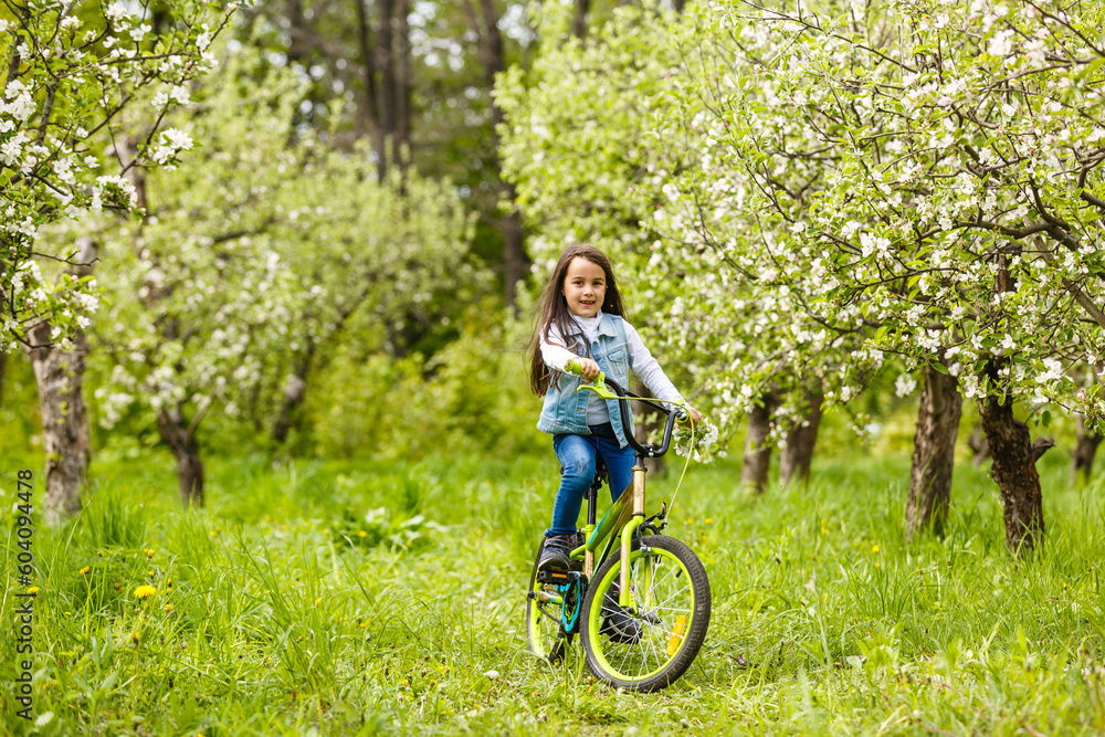 little girl with a bicycle near a flower