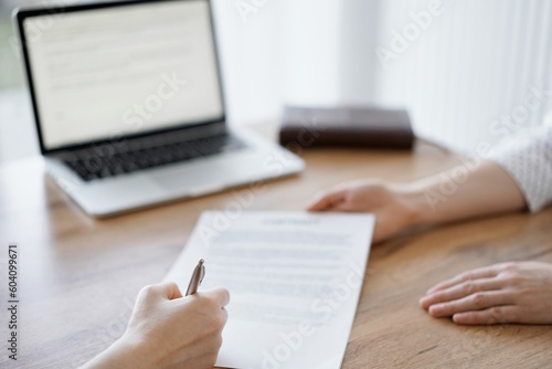 Business people signing contract papers while sitting at the wooden table in office, closeup. Partners or lawyers working together at meeting. Teamwork, partnership, success concept.