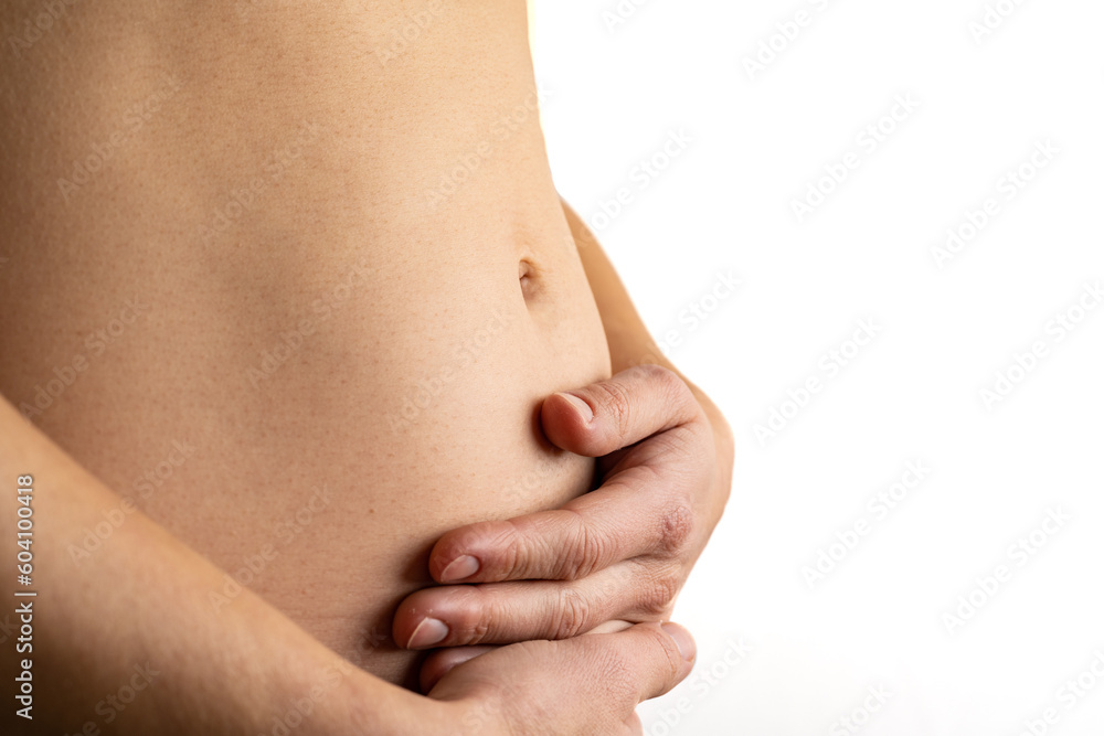 Very close up view of woman in first months of pregnancy gently holding her belly. Pregnancy first trimester - week 18. Close up. Side view. White background. Bright shot.