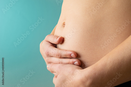 Obraz na płótnie Very close up view of woman in first months of pregnancy gently holding her belly