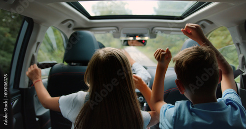 Two little boy and girl listens enjoys music and dancing while road trip. Children are playing in the car. Concept of journey.