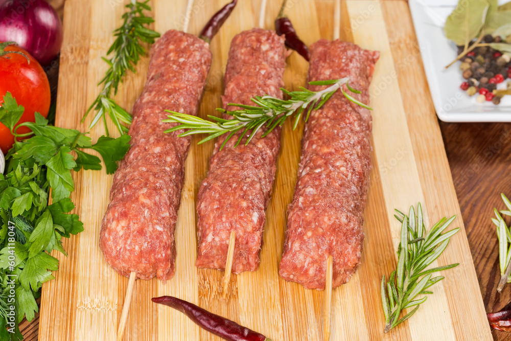 Raw lula kebab on cutting board among vegetables and spices Raw lula kebab on cutting board among vegetables and spices