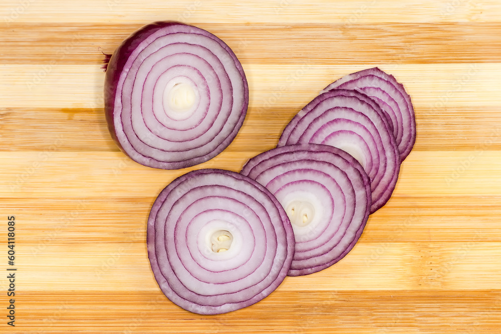 Partly cut bulb of red onion on a cutting board