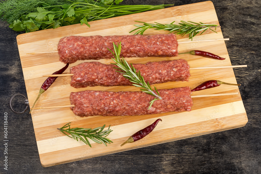 Raw lula kebab on the wooden skewers on cutting board Raw lula kebab on the wooden skewers on cutting board