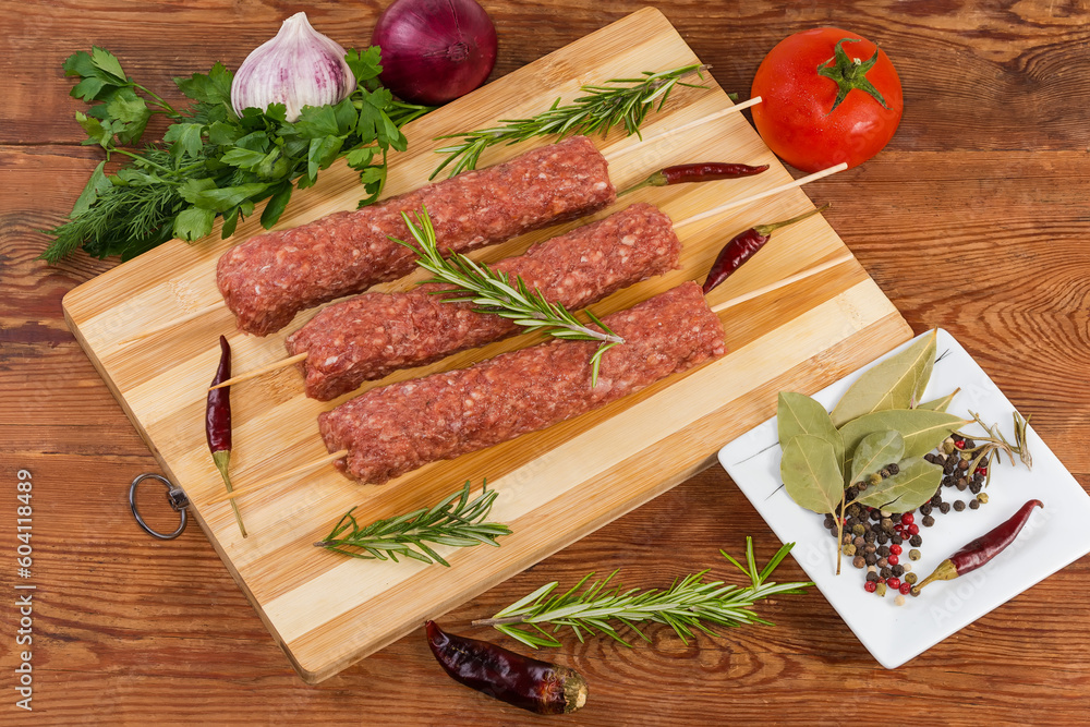 Raw lula kebab on cutting board among vegetables and spices Raw lula kebab on cutting board among vegetables and spices