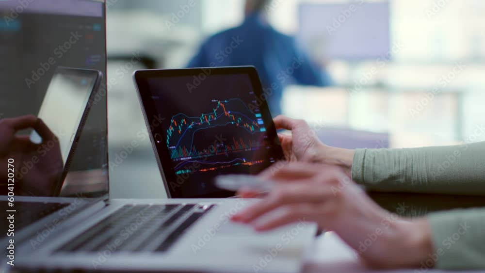 Close up of trader watch stock market graph on digital tablet and type on laptop