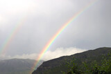 Beautiful rainbow over the mountain and gray sky. 